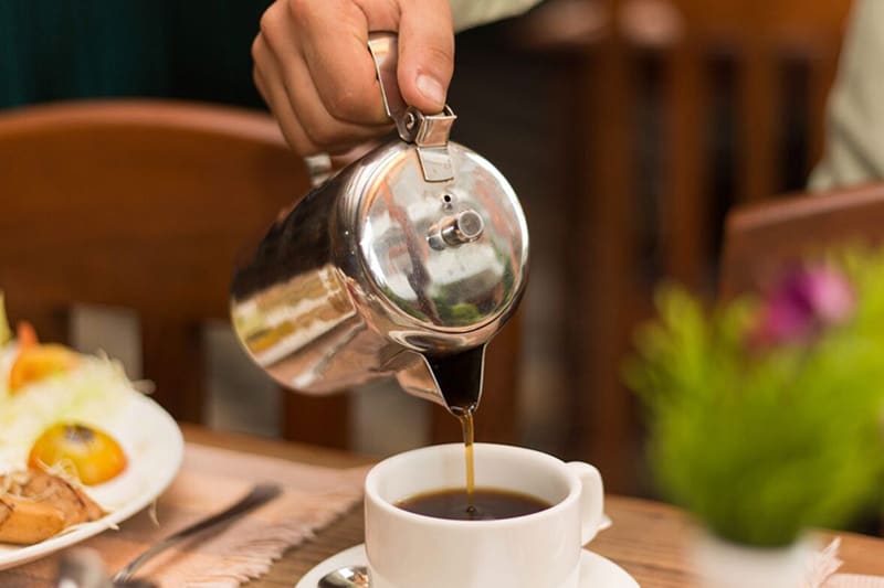 Coffee being poured at a breakfast table