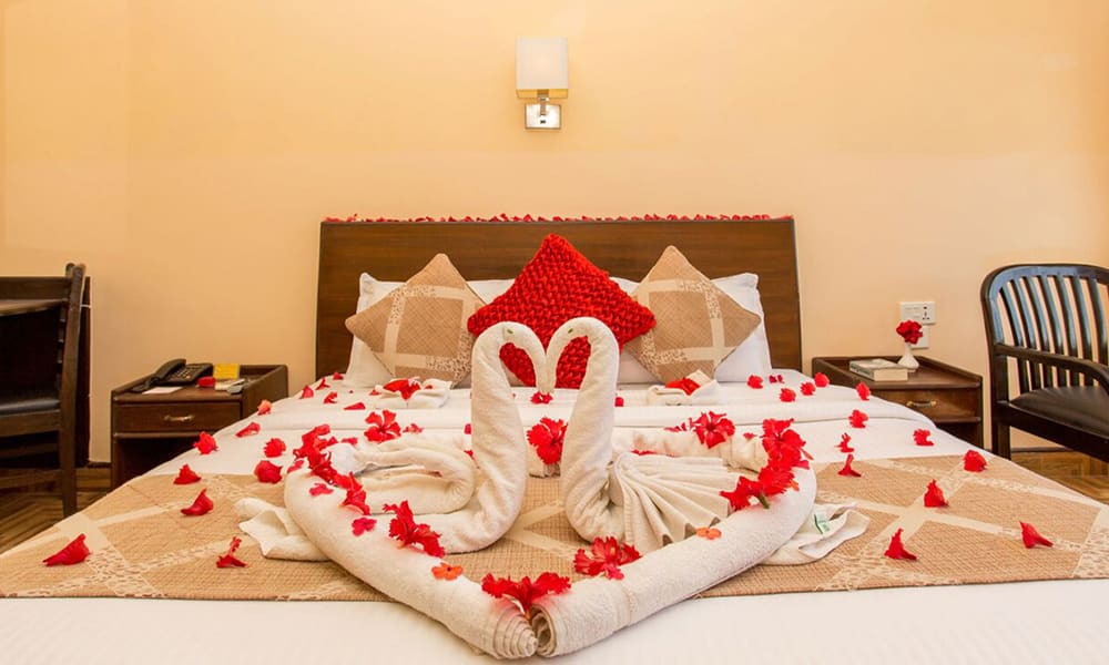 Honeymoon bed setup with a red heart cushion and towel swans