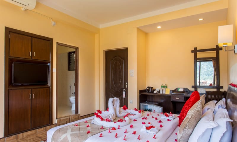 Decorated king bed with a wooden wardrobe and TV unit behind