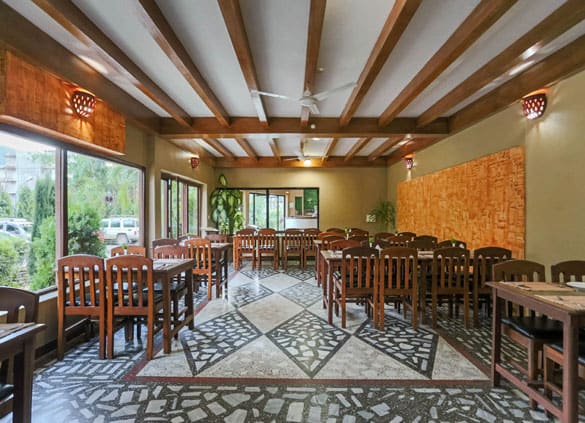Restaurant interior with a patterned stone floor and carved wooden panel