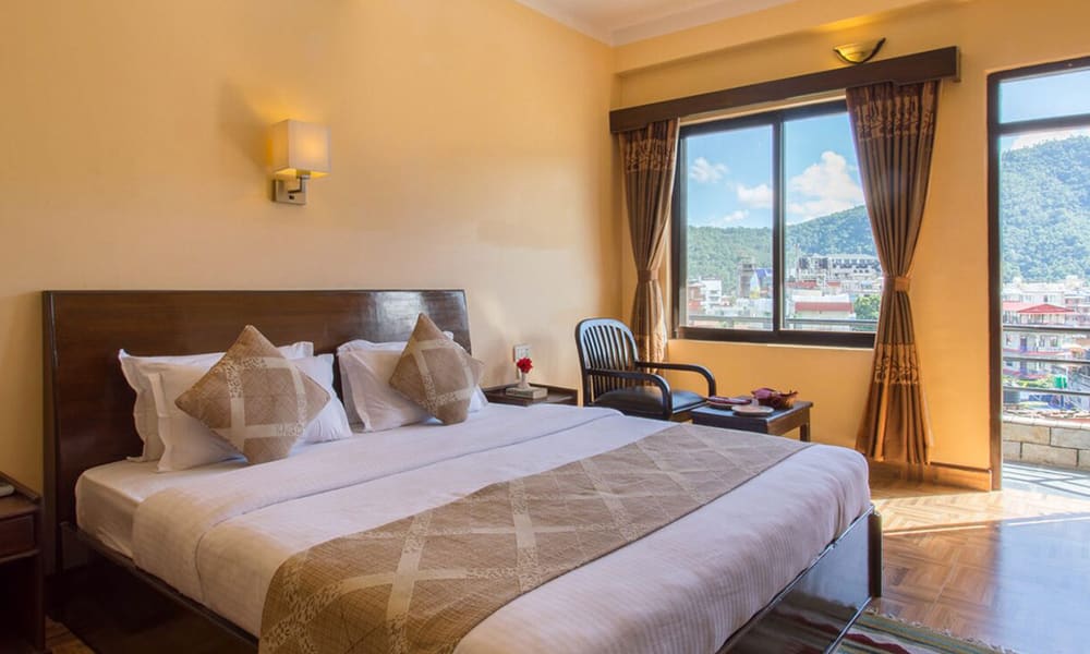 A king room with patterned bedding and a window onto green hills