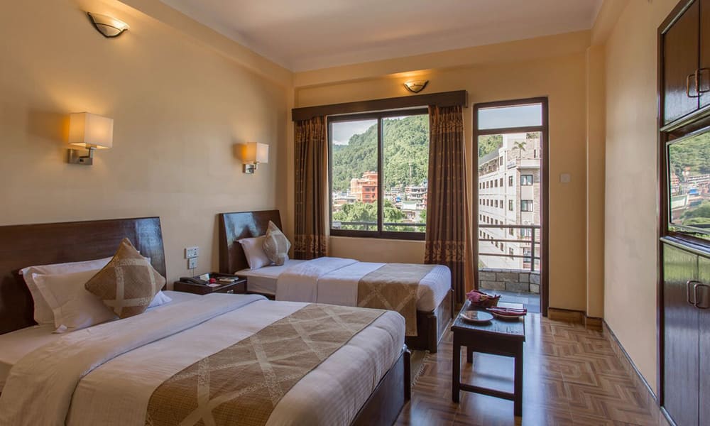 Twin room with a balcony door open to the town and hills
