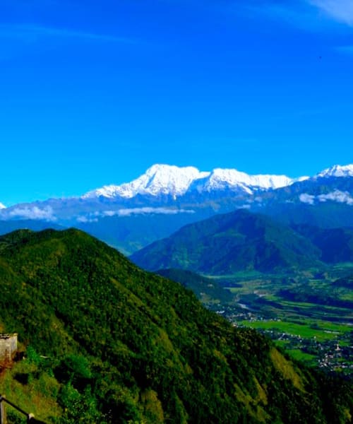 Snow peaks of the Annapurna range above green hills, seen from Sarangkot