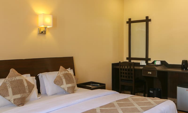 King bed beside a dark wooden writing desk and mirror