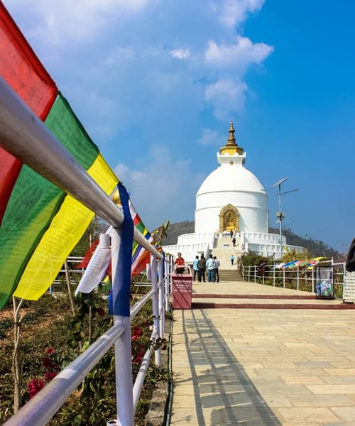 The white World Peace Pagoda with prayer flags along the approach